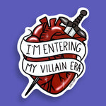 The vinyl sticker is in the shape of a human heart with a dagger on a purple background. The sticker reads I'm Entering My Villain Era.