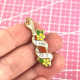 A hard enamel lapel pin being held in a hand. The pin is in the shape of a seam ripper. The lapel pin reads I Can Fix It.