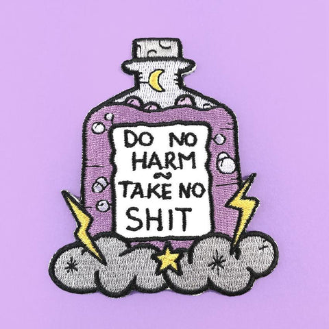 An iron on embroidered patch on purple background. The patch is purple and in the shape of a bottle with clouds and lightning bolts. The pin reads Do No Harm Take No Shit.