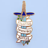 A hard enamel pin on a blue background. The pin is in the shape of a dagger and reads Fighting Invisible Battles.